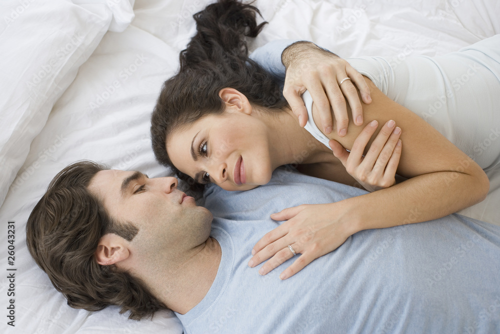 High angle view of Hispanic couple hugging in bed High angle view of Hispanic couple hugging in bed