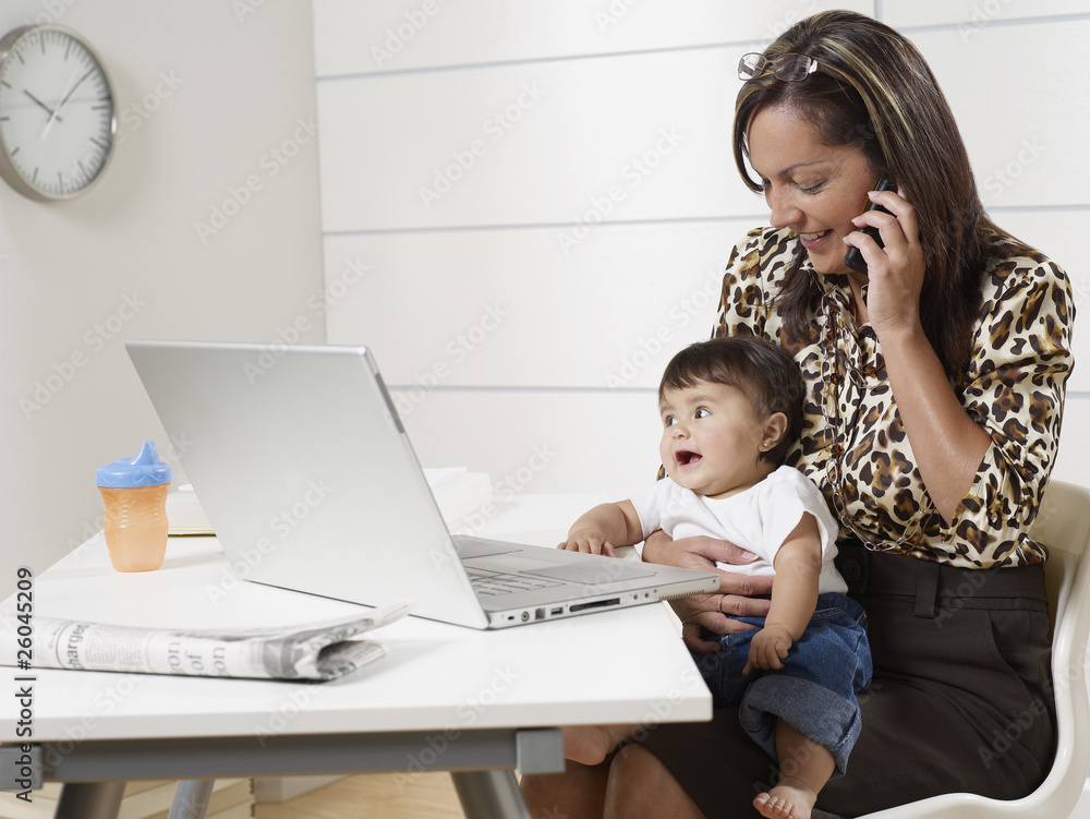 Hispanic working mother holding baby son and talking on phone Hispanic working mother holding baby son and talking on phone