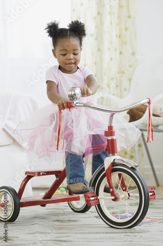 African American girl in costume riding tricycle