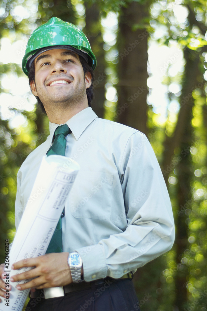 Hispanic architect holding blueprint and wearing green hard hat Hispanic architect holding blueprint and wearing green hard hat