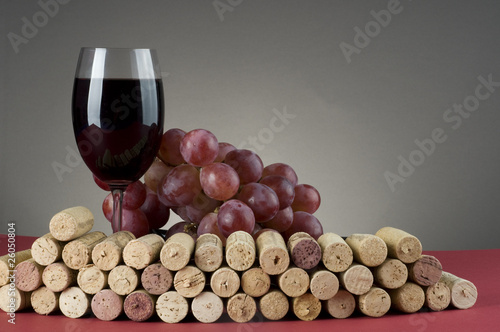 Red wine glass with grape and corks.