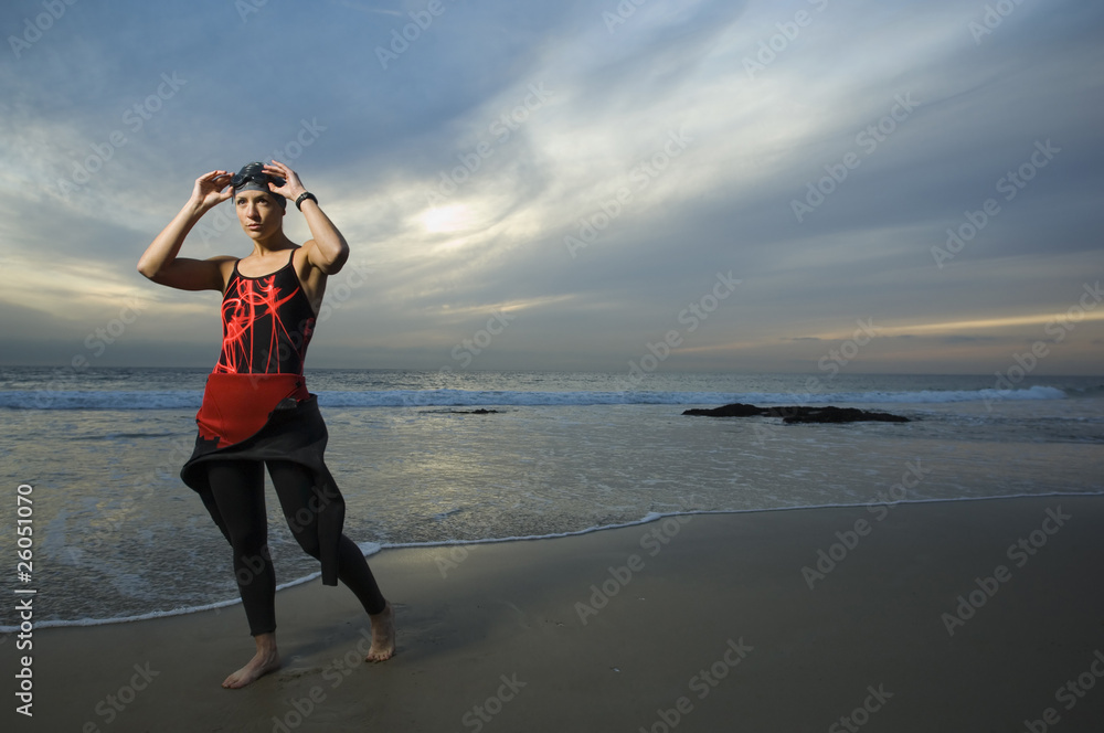 Woman wearing wetsuit on beach at sunset Woman wearing wetsuit on beach at sunset