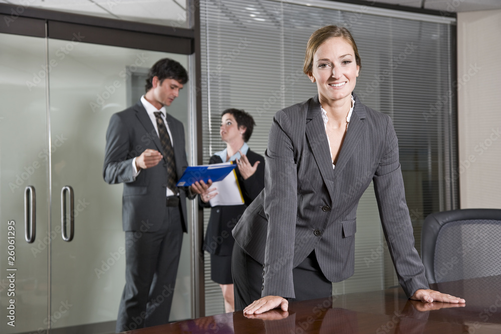 Confident businesswoman, colleagues in background Confident businesswoman, colleagues in background
