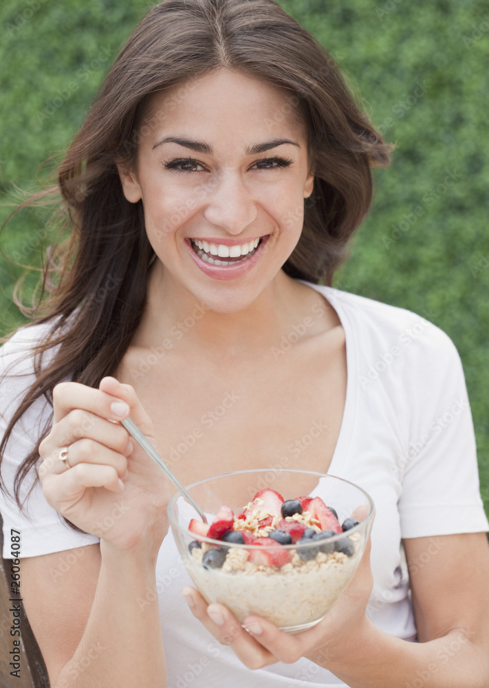 Hispanic woman eating cereal with fresh fruit Hispanic woman eating cereal with fresh fruit