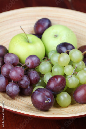 Bowl with fresh organic apples  grapes and plums