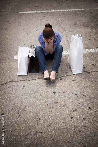 lost woman sitting in parking lot with shopping bags covering fa photo