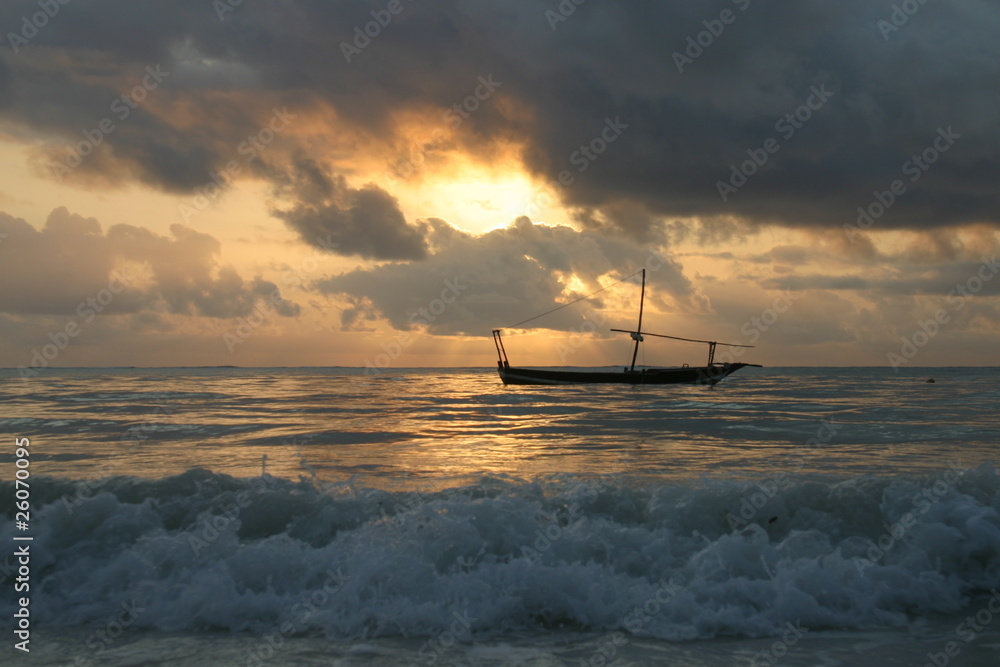 vague et barque sous coucher de soleil