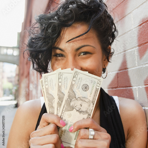 Mixed race woman holding twenty dollar bills