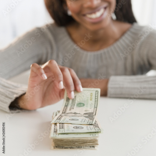 Mixed race woman taking money from stack