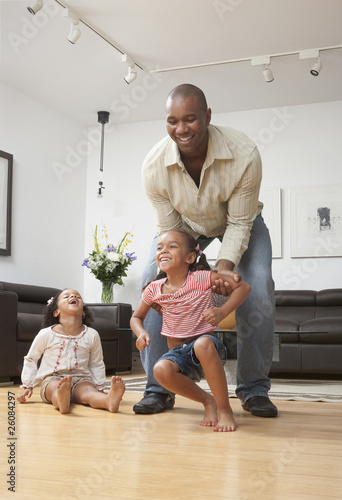 African American father playing with daughters in living room photo