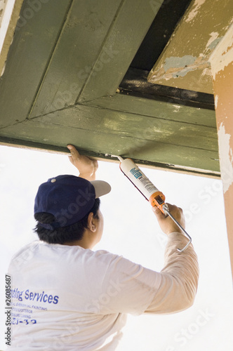 Latin man caulking roof eaves