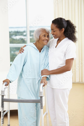 African American nurse helping senior woman with walker