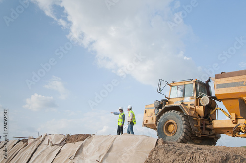 Canvas Print Hispanic construction workers in field with dump truck