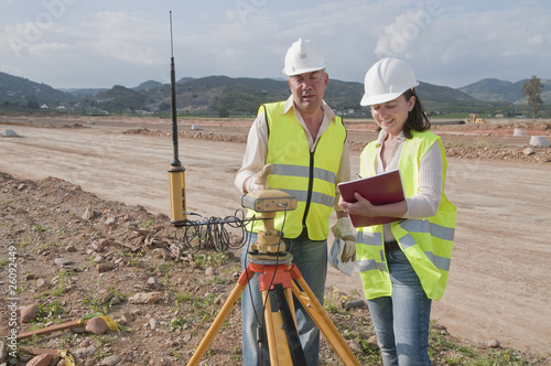 Construction workers examining equipment in field photo