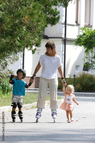 mother with two children rollerskaing in park