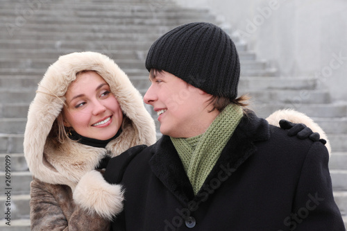 girl in coat with hood and man in black dress smiling
