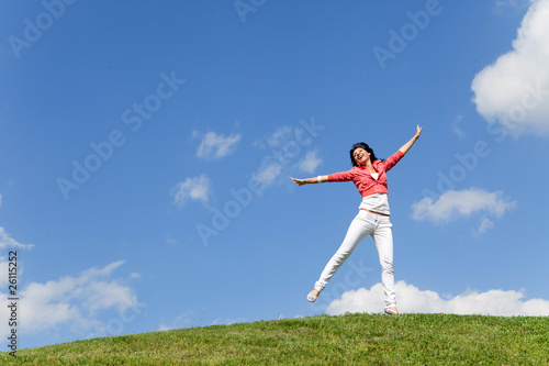 pretty young woman jumping on green grass