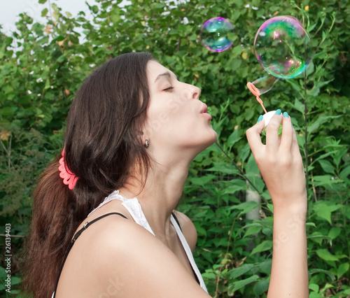 Young girl blowing soap bubbles in autumn park