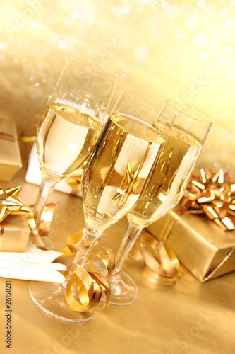 Glasses of champagne with golden decoration on background
