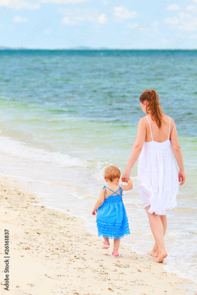 Mother and baby walking along tropical beach Mother and baby walking along tropical beach