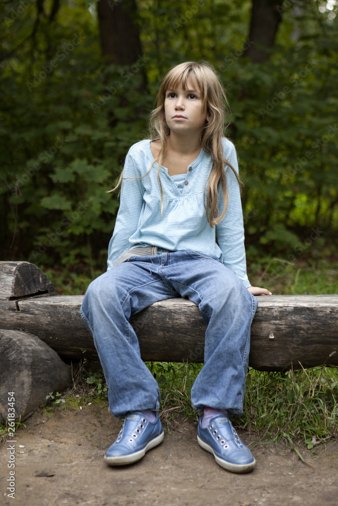 Obraz premium serious little girl nine years old sitting on bench in park