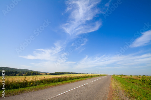 Summer landscape with rural road and cloudy sky