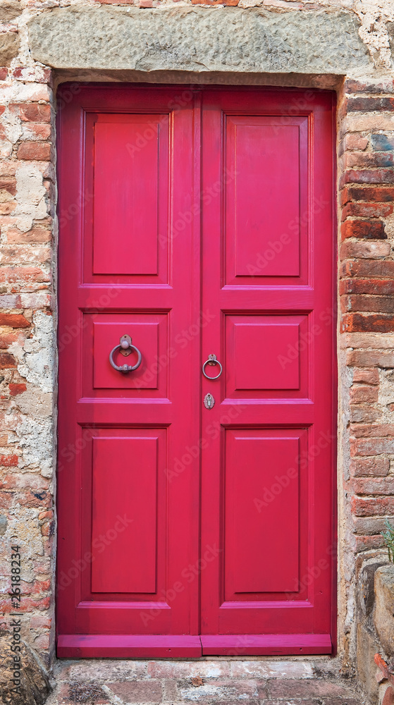 Wooden closed pink door with brick wall around it.