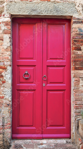 Wooden closed pink door with brick wall around it.
