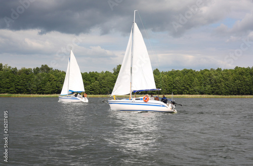 white yachts sail in the lake , Mazury, Poland