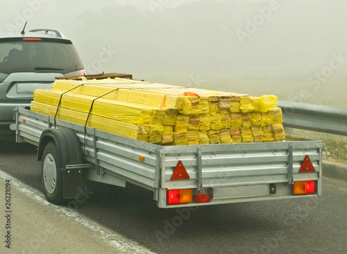 Canvas Print Auto car trailer laden with wooden planks building material at foggy road
