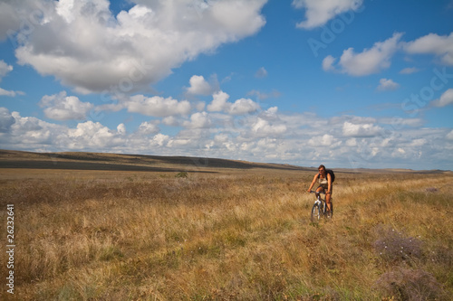 Fototapeta Naklejka Na Ścianę i Meble -  Women with bike on meadow on sky background