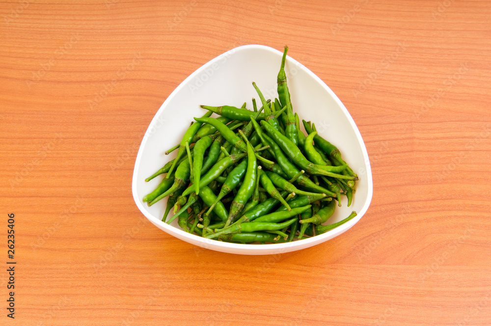 Hot peppers in the plate on wooden table Hot peppers in the plate on wooden table