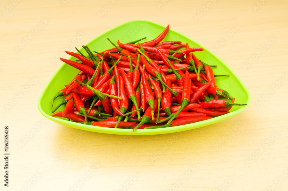 Hot peppers in the plate on wooden table Hot peppers in the plate on wooden table