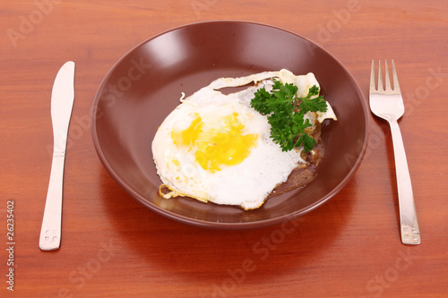 Frying egg with fork and knife on the table
