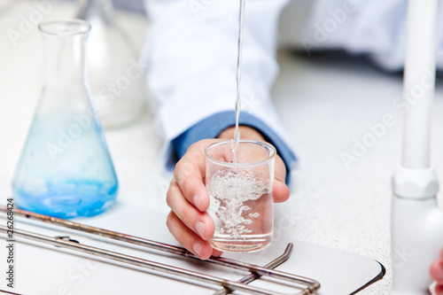 Close-up of a male scientist pouring liquid into a becher
