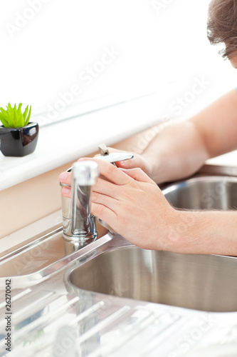 Close-up of a young man repairing his sink in the kitchen