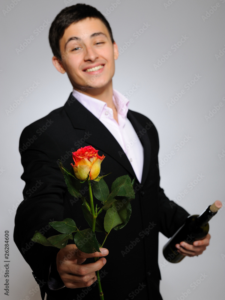Handsome romantic young man holding rose flower and vine bottle Handsome romantic young man holding rose flower and vine bottle