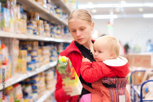 Young mother with baby daughter shopping in supermarket