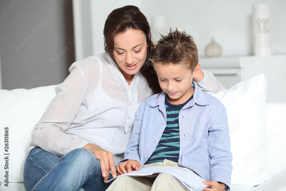 Little boy and mother sitting on sofa at home with book Little boy and mother sitting on sofa at home with book