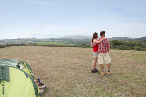 Couple standind by camp tent and looking at scenery