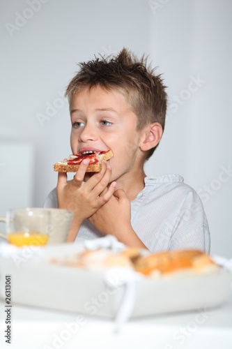 Little blond boy eating slice of bread