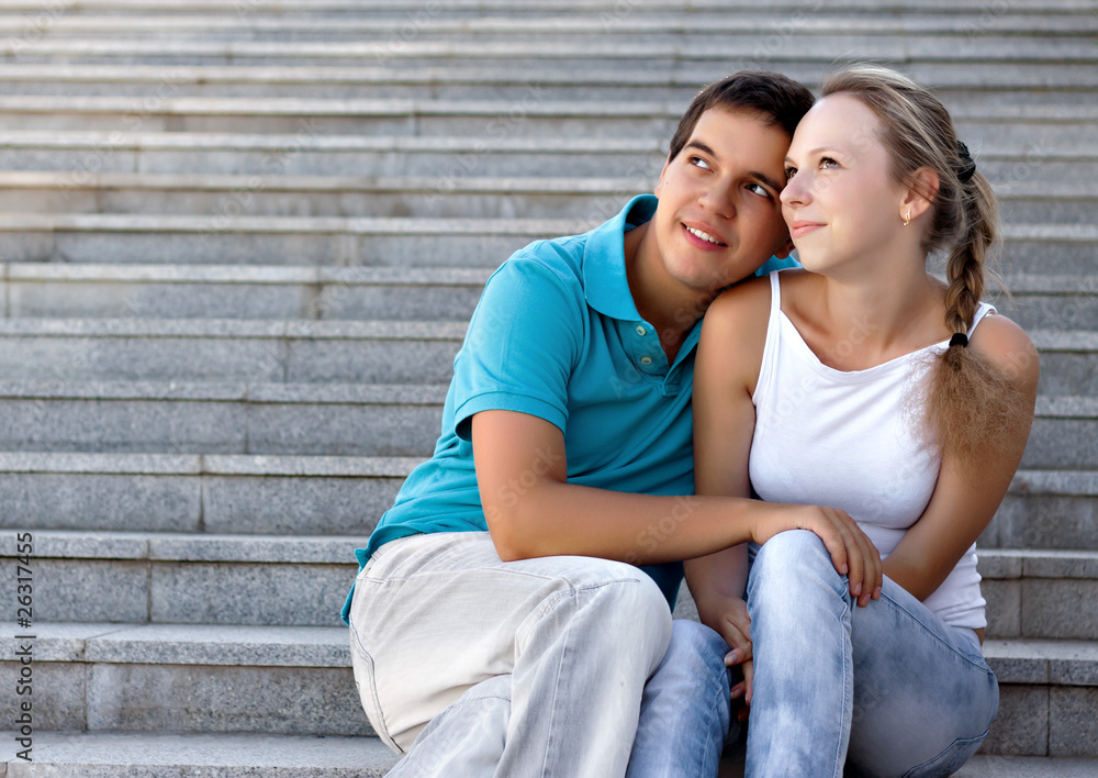 young loving couple sitting on stairs and looking in the sky young loving couple sitting on stairs and looking in the sky