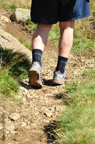 Man runs along a mountain path, closeup feet, sneakers