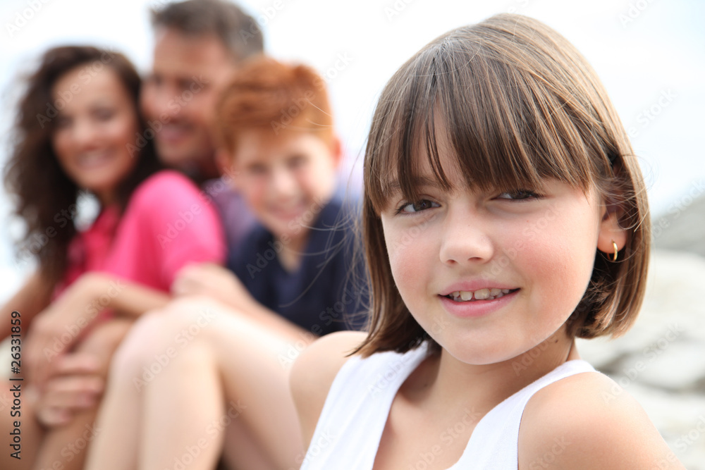 Little girl looking at camera and family in background Little girl looking at camera and family in background