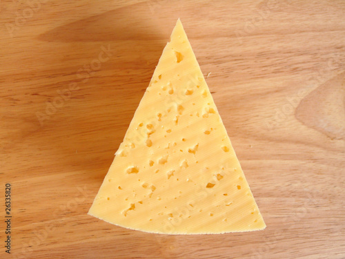 A piece of cheese on a cutting board. Isolation