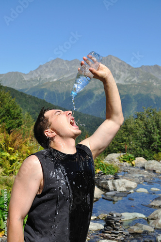 The young man eagerly drinking water from plastic bottles,