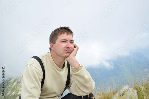 A young man sits on a hilltop