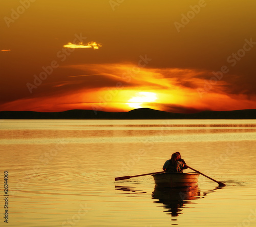 Couple rowing boat at sunset