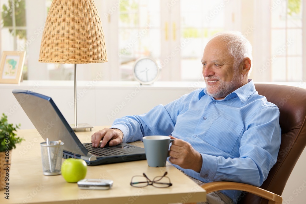 © nyul - Smiling senior man using laptop