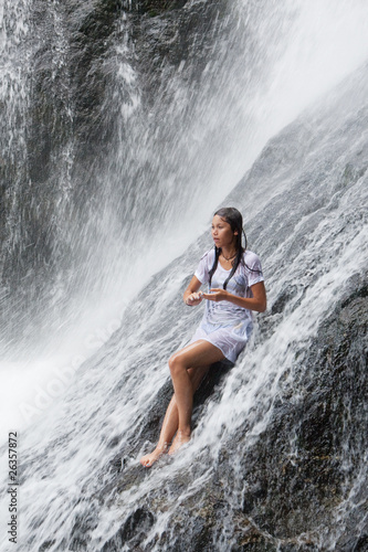Mädchen sitzt im Wasserfall